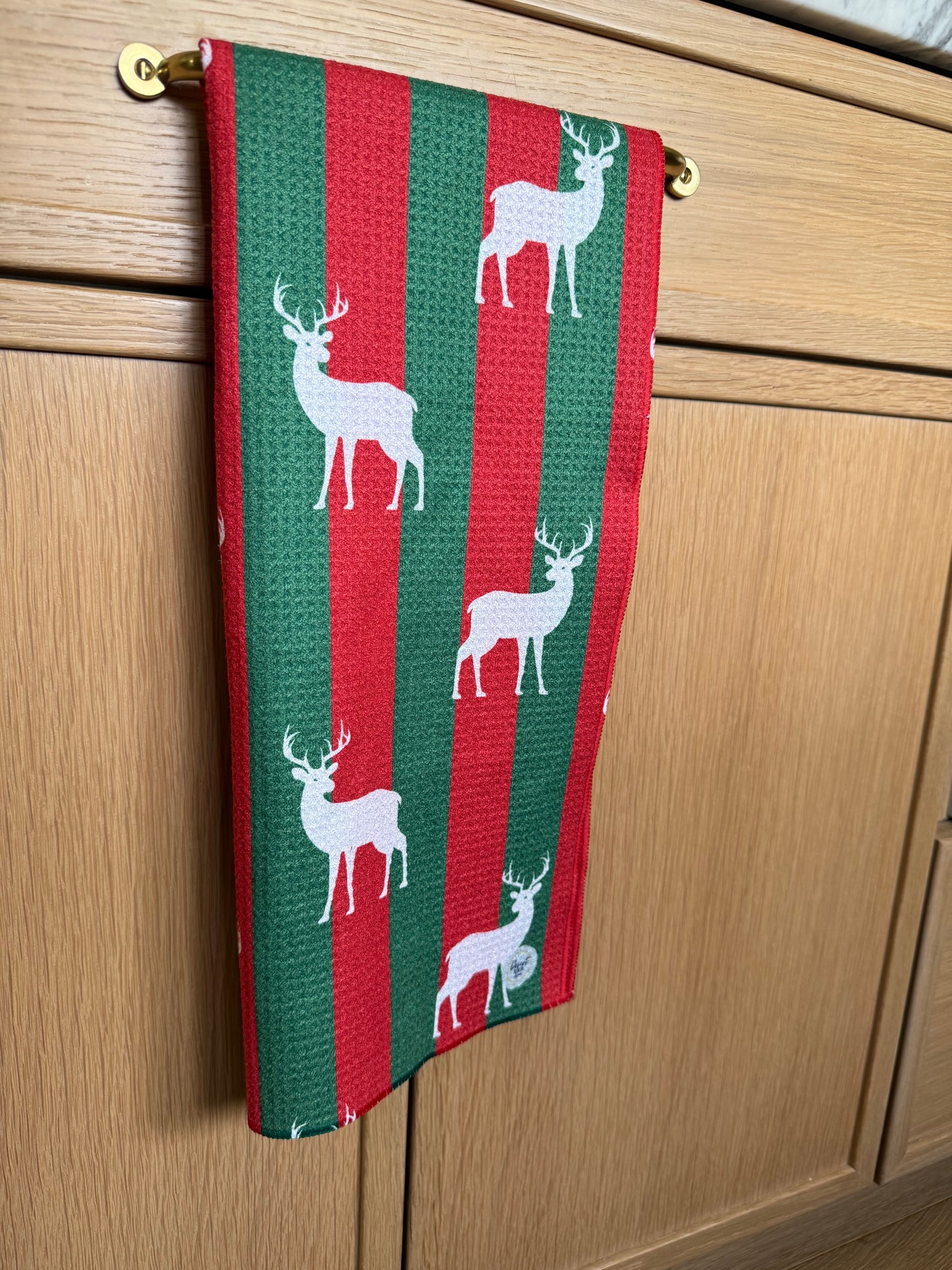 red and green striped towelwith deer pattern hanging on a wooden surface