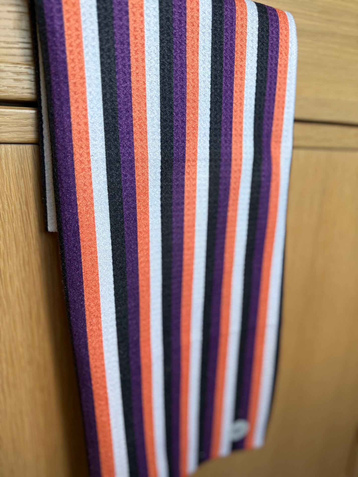 Striped towel with purple, orange, and white stripes on a wooden surface