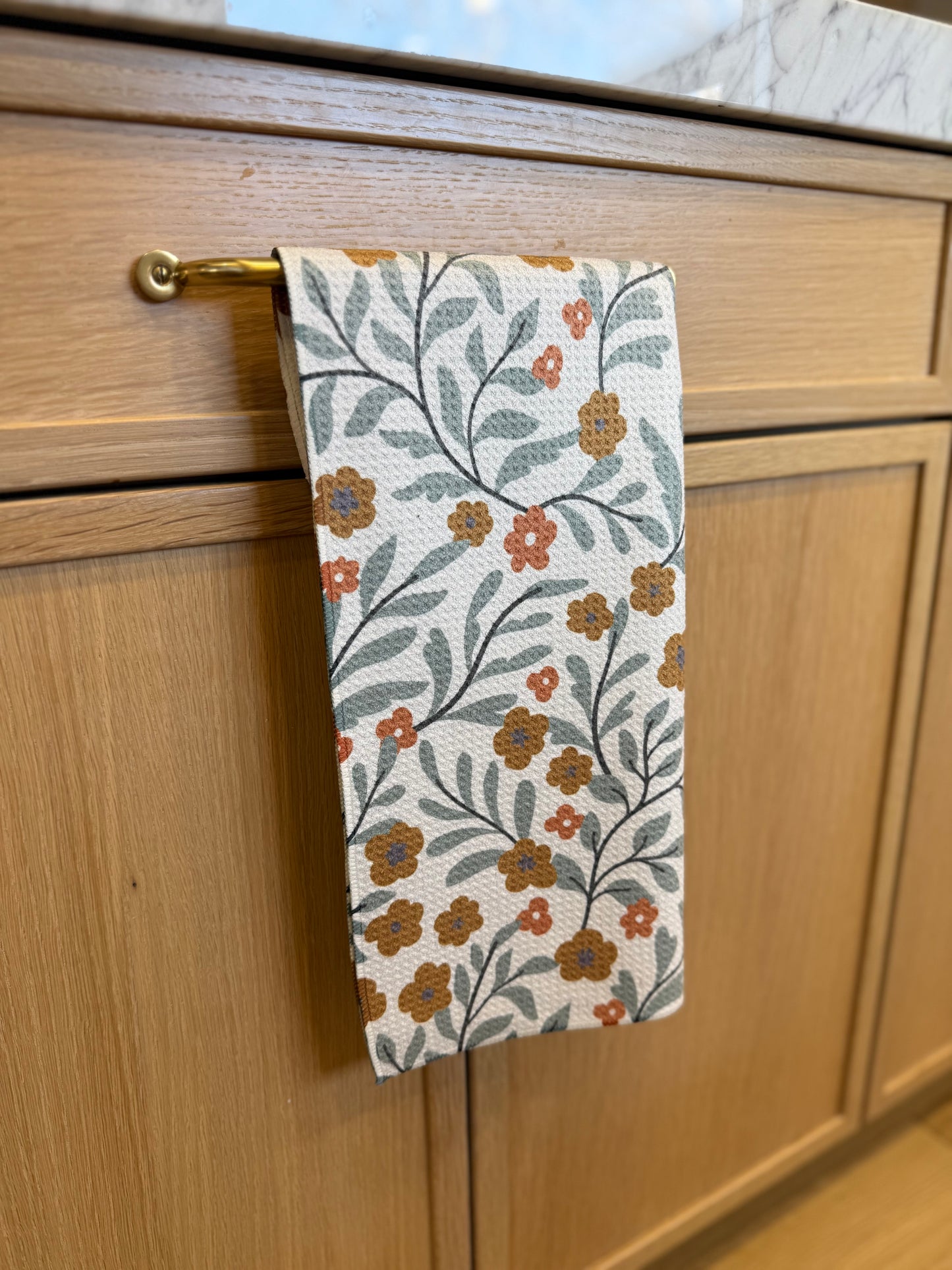 FLORAL TOWEL HANGING ON A WOOD CABINET
