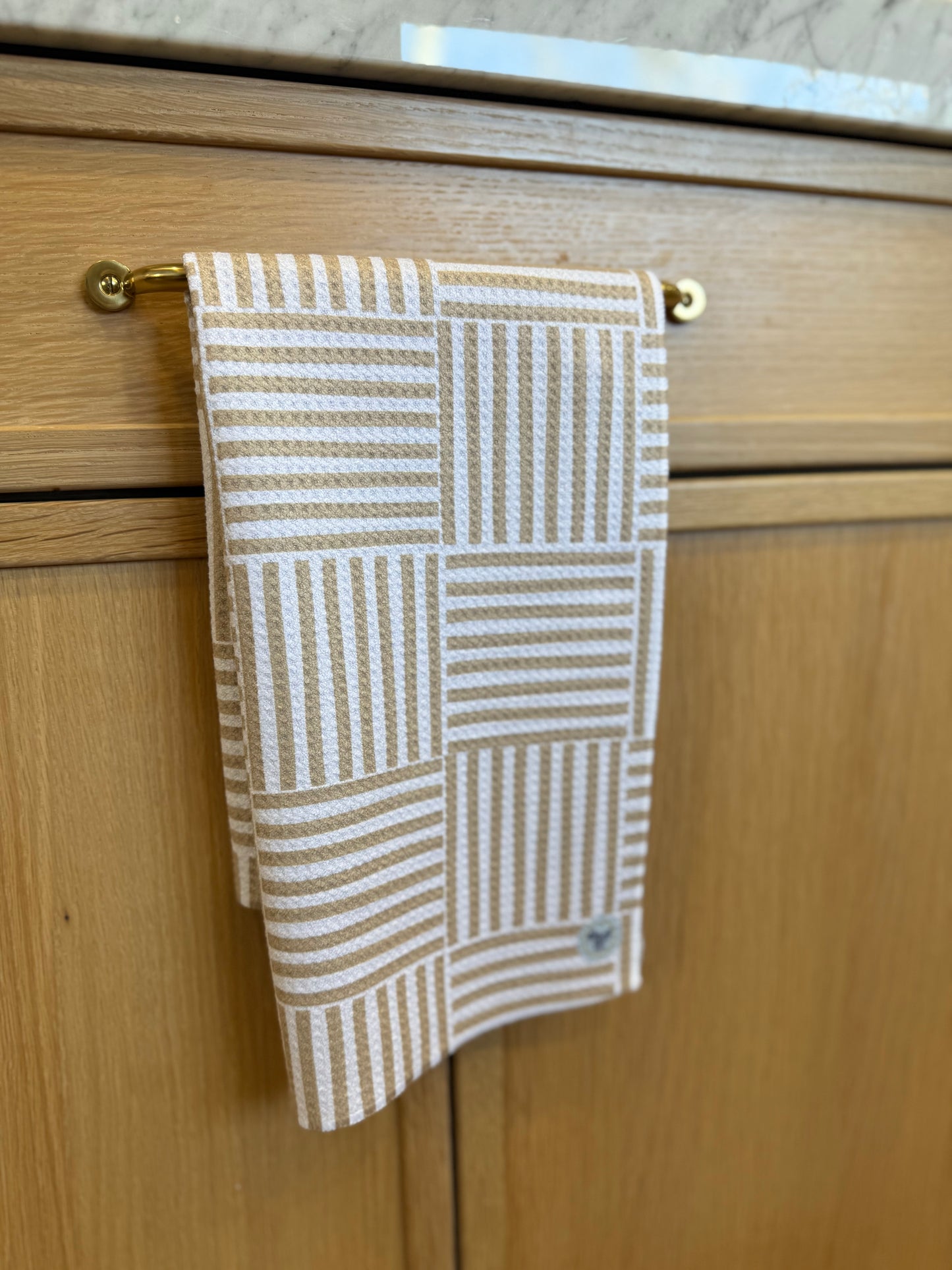CHECKERED towel hanging on a wooden cabinet with a gold handle.
