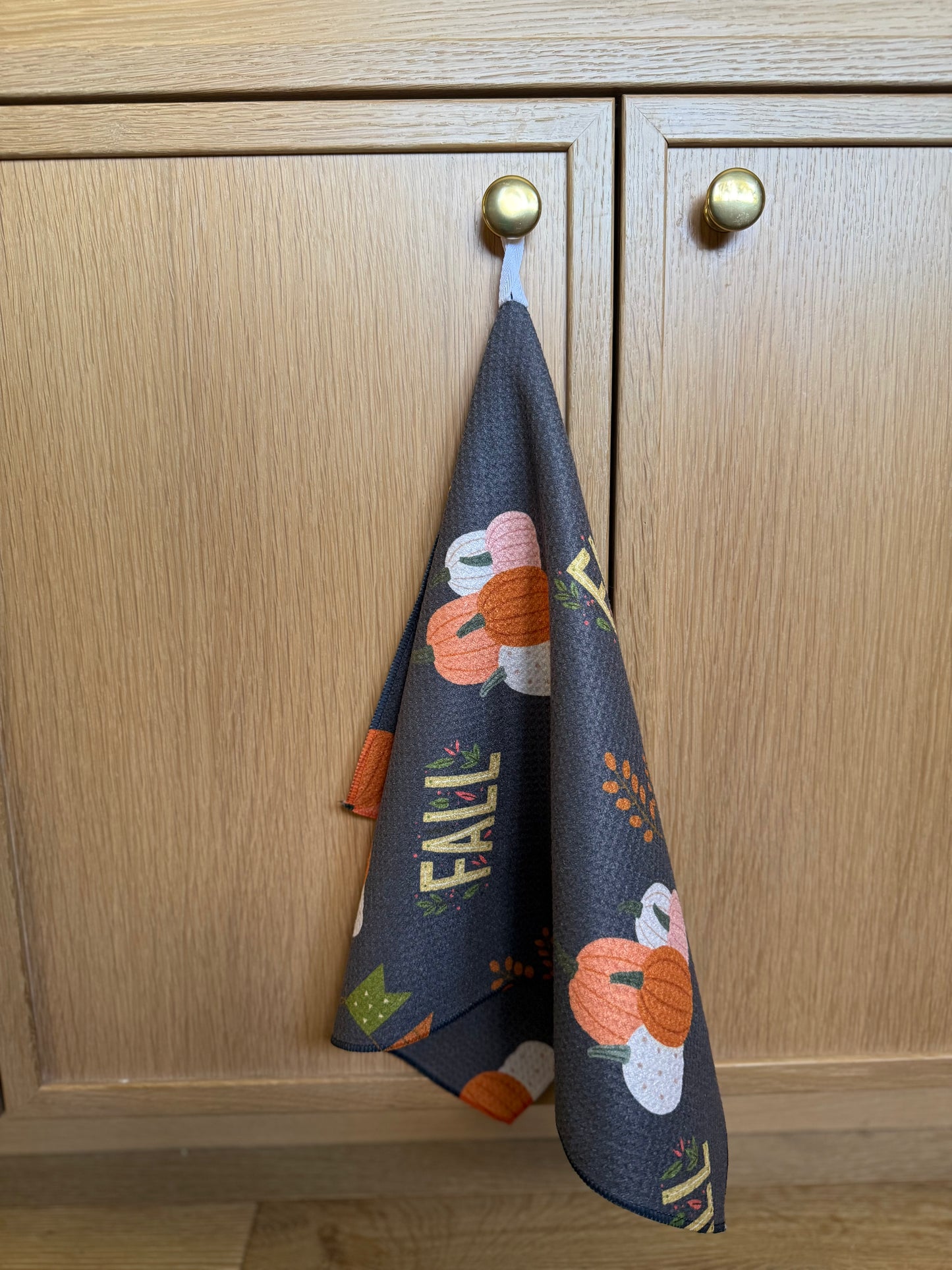fall themed dish towel handing on a cabinet knob
