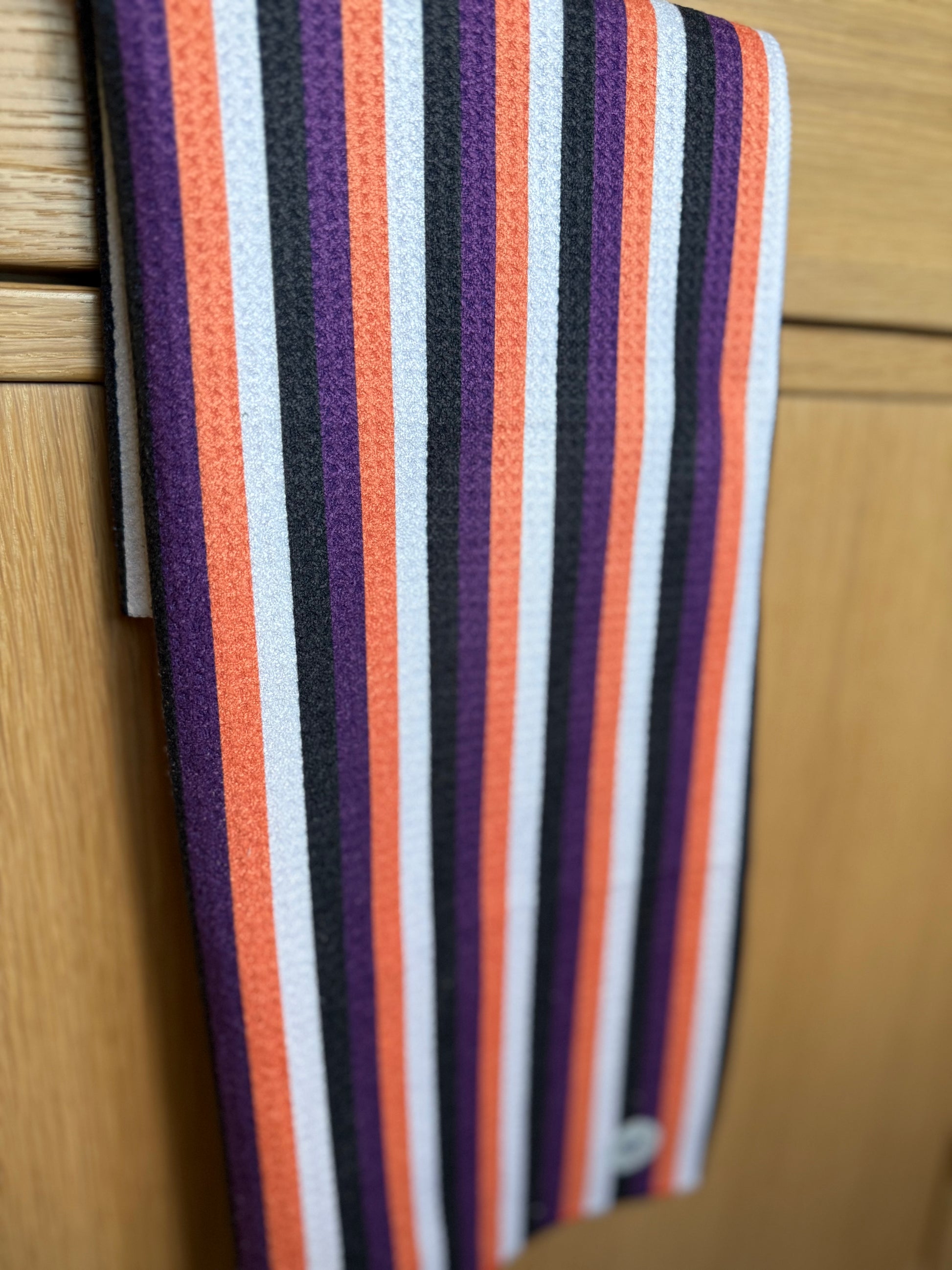 Striped towel with purple, orange, and white stripes on a wooden surface