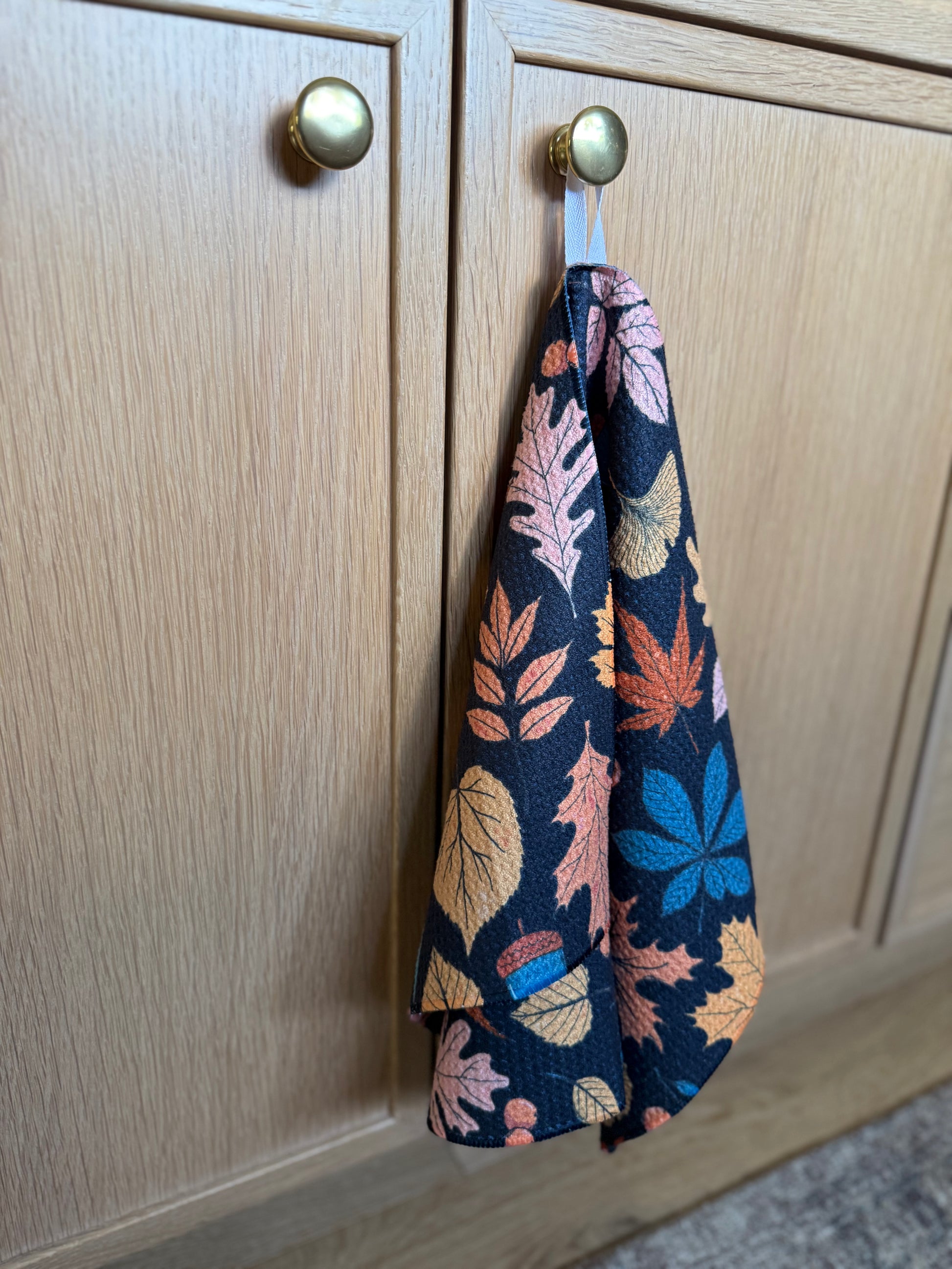 leaf-patterned towel hanging on a wooden cabinet door.