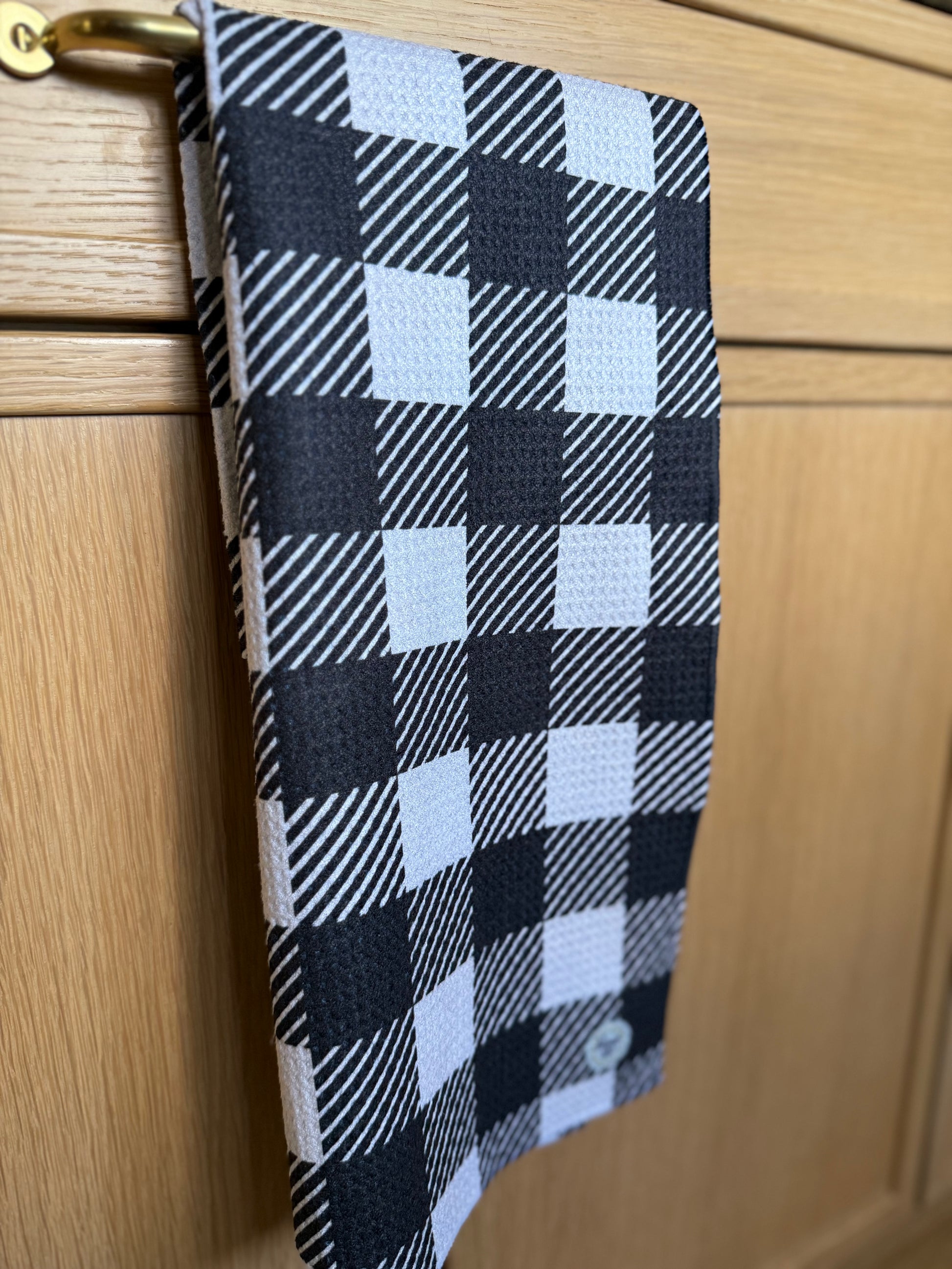 Black and white checkered towel hanging on a wooden cabinet.