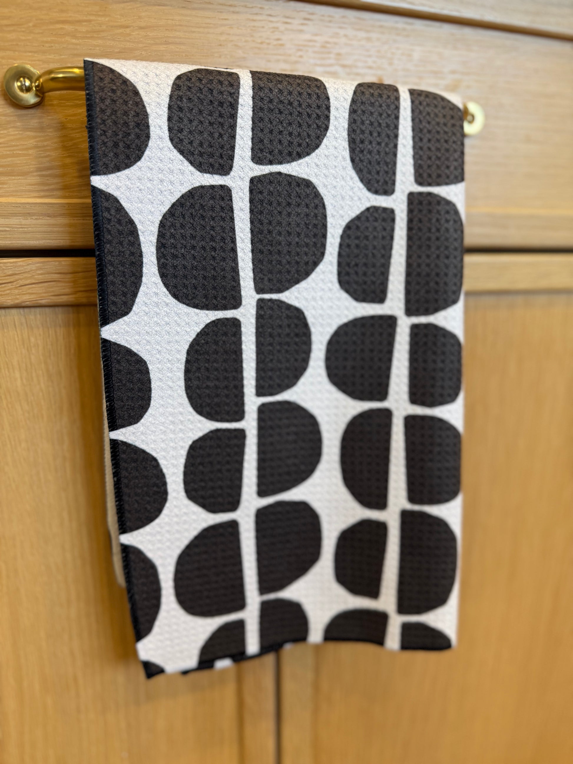 Black and white patterned towel hanging on a wooden cabinet.