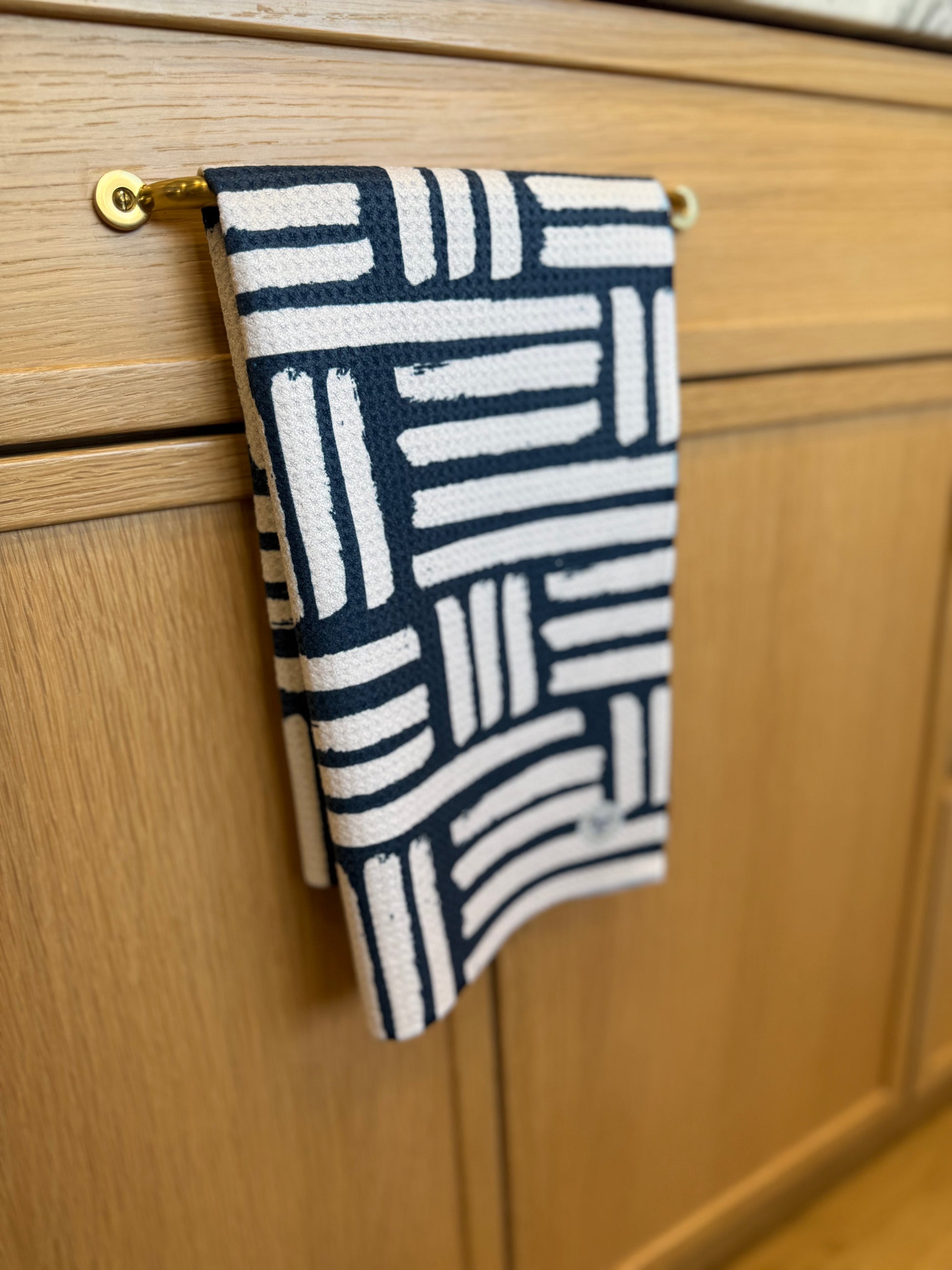 Navy and white patterned towel hanging on a wooden cabinet.
