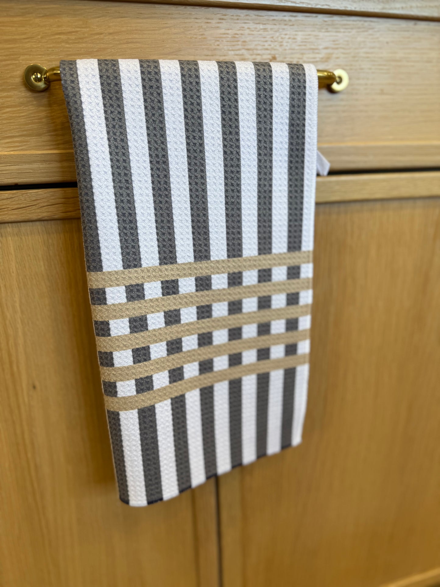 Striped towel hanging on a wooden cabinet handle