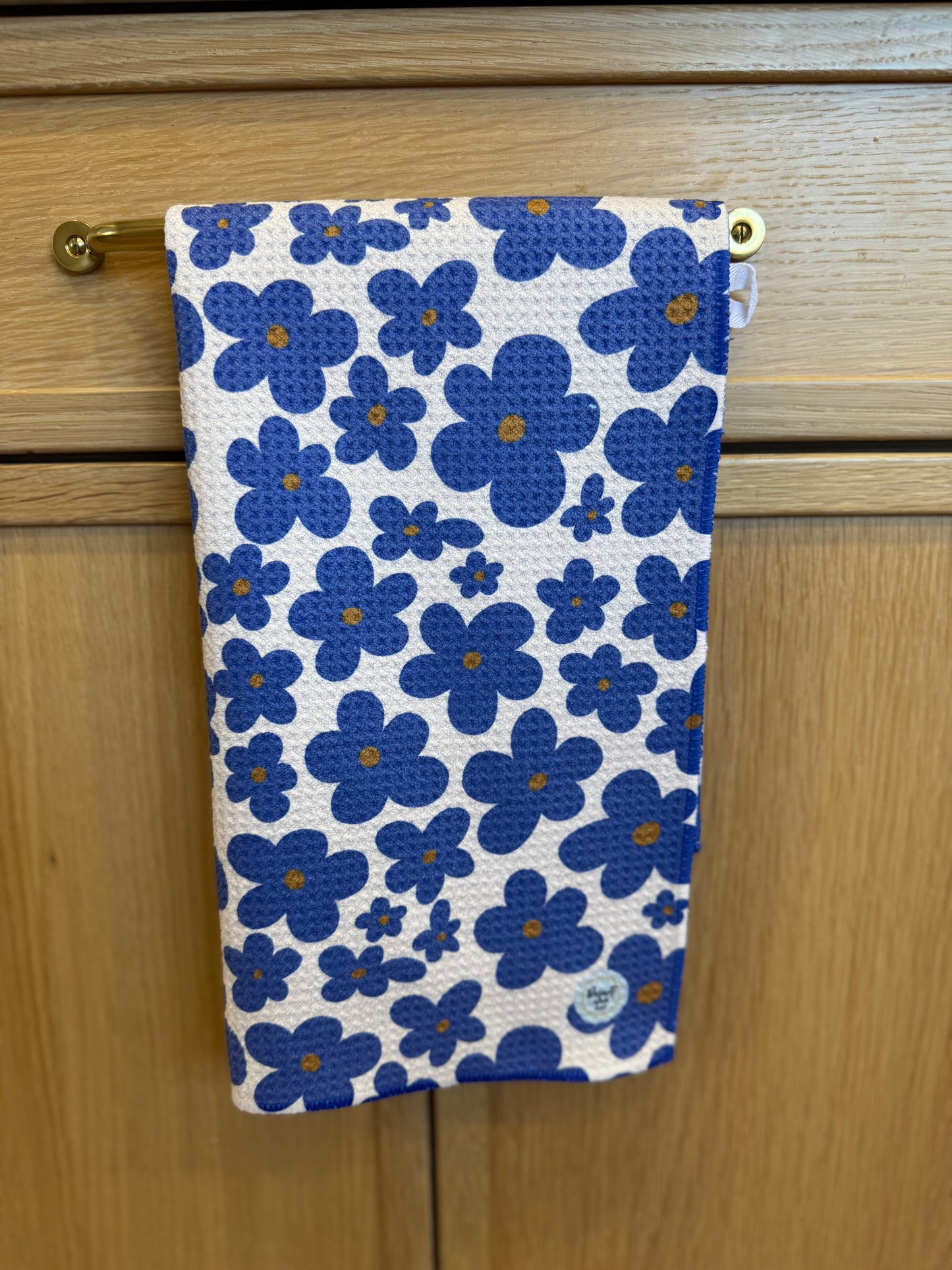 Floral-patterned towel hanging on a wooden cabinet.