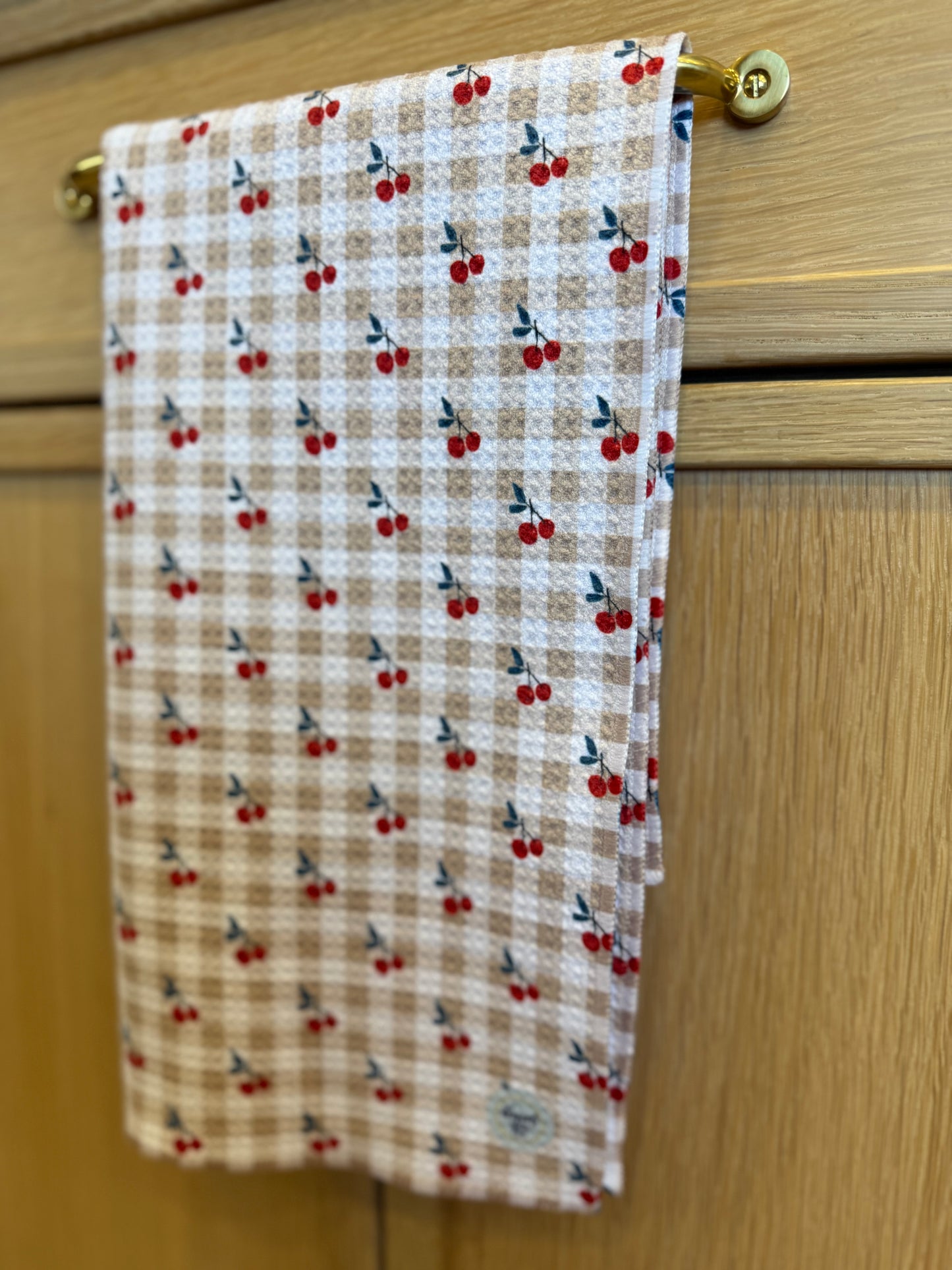 Towel with cherry pattern hanging on a wooden door handle