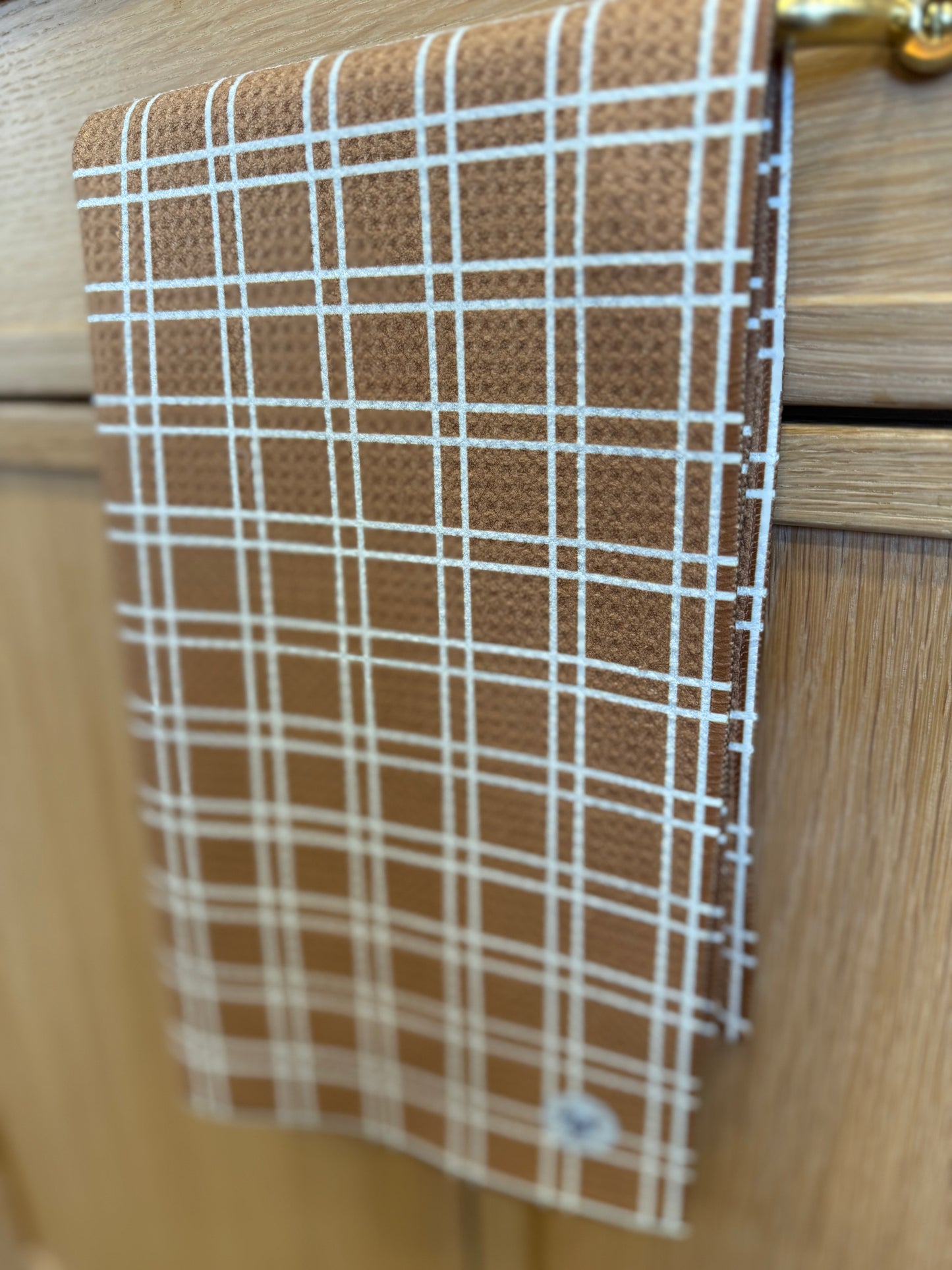Brown and white checkered towel hanging on a wooden cabinet.