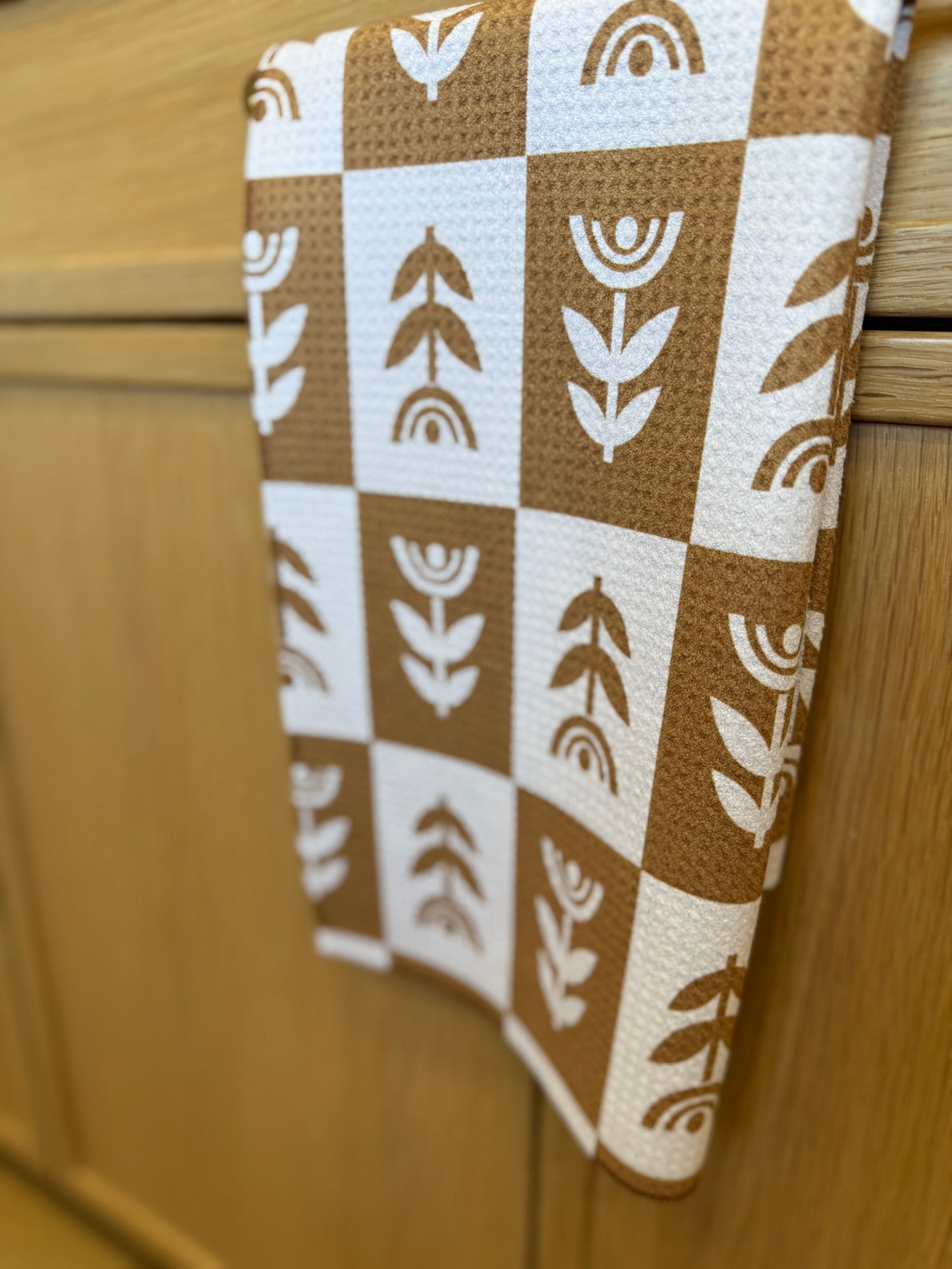 Brown and white patterned towel hanging on a wooden cabinet.