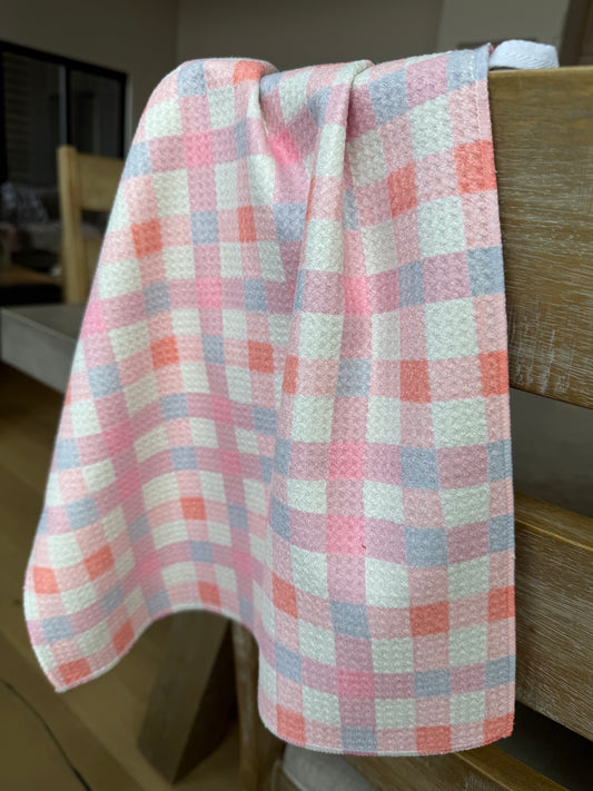 Plaid fabric with pink, blue, and white pattern on a wooden surface